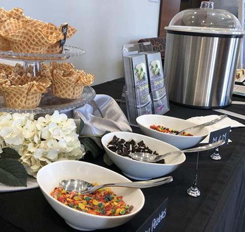 Sundae toppings in bowls alongside an ice cream urn and waffle bowls.