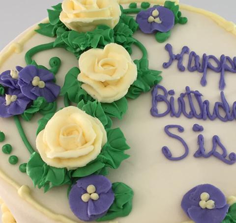 A cake decorated with roses and the words Happy Birthday Sis.