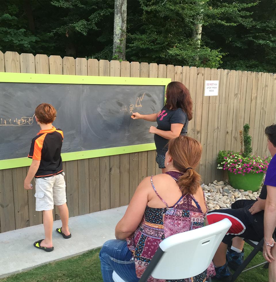 People writing on an outdoor chalkboard.