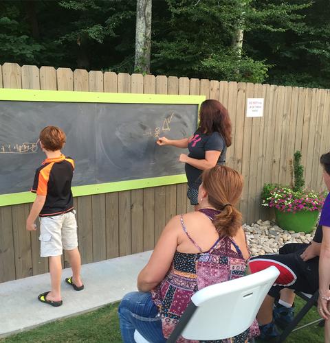 People writing on an outdoor chalkboard.
